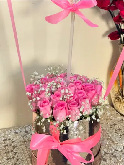 The base of our hot air balloon arrangement, showcasing a dense cluster of beautiful pink roses and delicate baby's breath nestled in a reflective silver box with a matching pink bow.