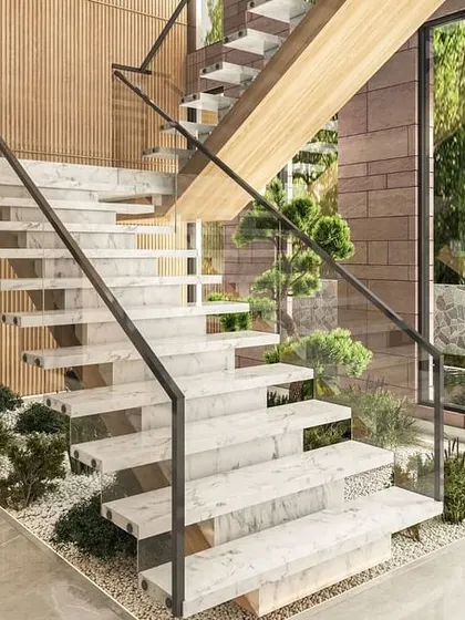 The floating staircase in our Jammu project is a sculptural element, with marble steps and a minimalist glass railing. An indoor garden bed beneath the stairs reinforces the home's connection to nature and biophilic design principles.