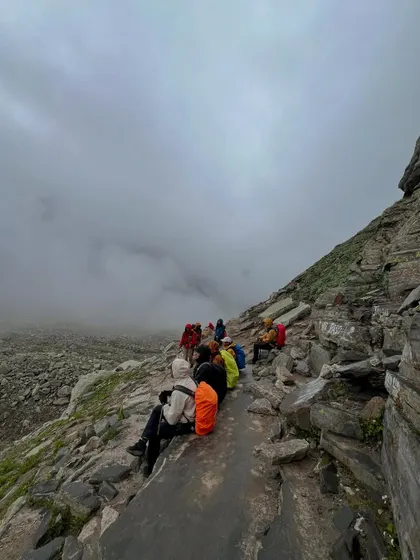 A moment of rest on the rocky ascent to Hampta Pass, with clouds rolling in below.