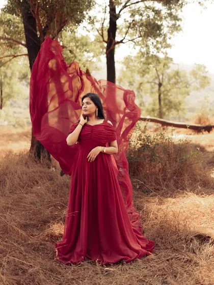 Lost in thought in a sun-drenched field. This shot shows how the sheer red fabric of the trail gown catches the light so beautifully, adding a dreamy quality to the photo.