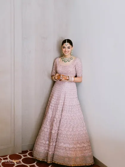 A full-length portrait of the bride, her smile radiant, looking elegant and poised in her beautiful pink lehenga.