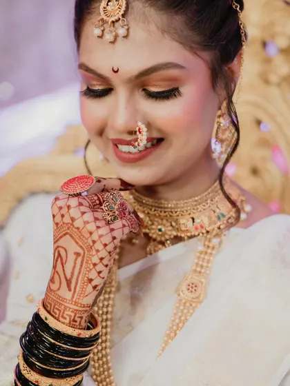 The bride showing off the initial 'N' in her mehndi design, a personal and sweet detail captured forever.
