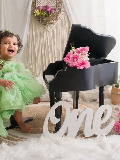 Twirling into her first birthday with the biggest smile. This photo captures the pure, energetic joy of a one-year-old in a beautiful, light-filled studio setting.