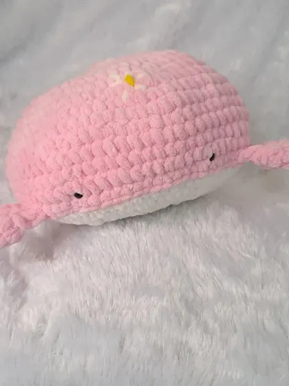 Another view of the adorable pink whale pillow, showcasing its soft, plush texture and friendly, hand-stitched eyes.