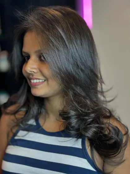 A happy client showing off her new layered hairstyle. The cut is tailored to complement her face shape, with soft layers that add texture and movement.