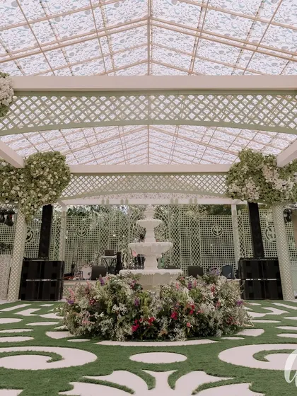 The centerpiece of the event space was a classic three-tiered fountain surrounded by a lush floral installation. The custom-cut astroturf with a baroque pattern adds a unique and playful design element.
