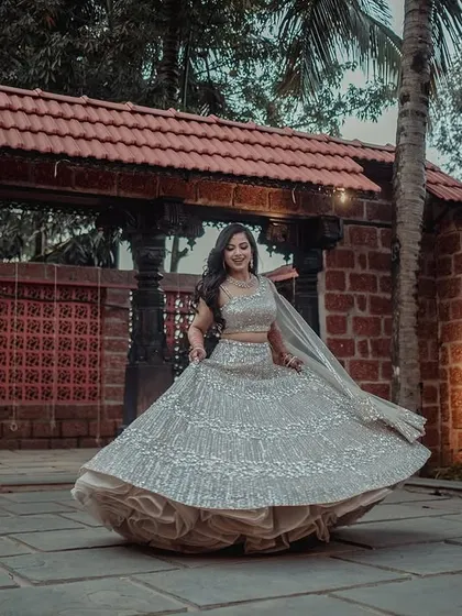 A beautiful twirling shot of the bride, Ashwini, in her shimmering silver lehenga at The Peacock Grove.