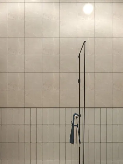 A minimalist bathroom design using two types of tiles. The vertically laid subway tiles on the lower half and the larger square tiles above are separated by a clean black line, creating a simple yet effective design.