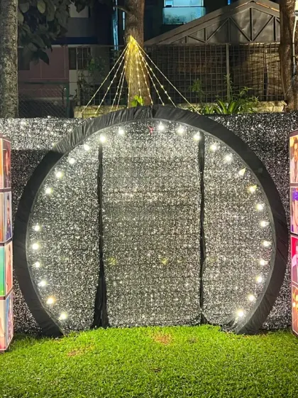 A personalized Bollywood-themed photo booth, featuring a glittering silver backdrop and lightboxes showcasing photos of the couple's favorite actors.