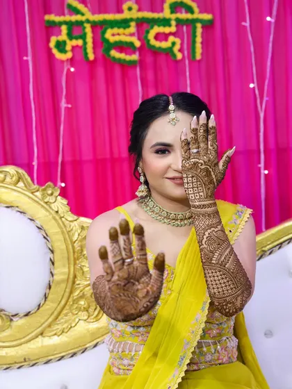 A playful pose that highlights both the makeup and the detailed henna art.