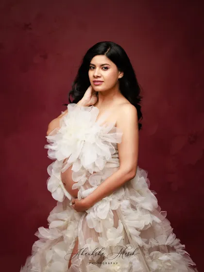 This unique gown, adorned with large, soft fabric flowers, creates a beautiful texture and a truly artistic statement for a maternity portrait.