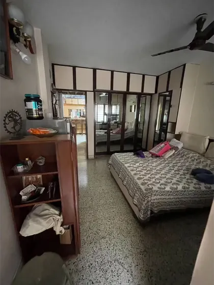 **BEFORE:** A guest bedroom with dated, heavy built-in wardrobes and dark terrazzo flooring, making the room feel small and dim.