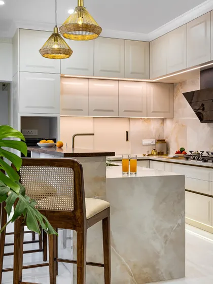 A kitchen should be both beautiful and highly functional. In this home, I designed a bright, open kitchen with a two-tiered breakfast counter and shaker-style cabinetry. The warm taupe and white palette, paired with finely veined marble, creates a clean, minimalist feel that is still warm and inviting.
