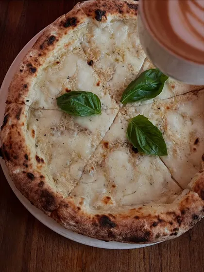 A beautiful shot of our Pizza Bianca, a white pizza that pairs perfectly with a hot cup of coffee.