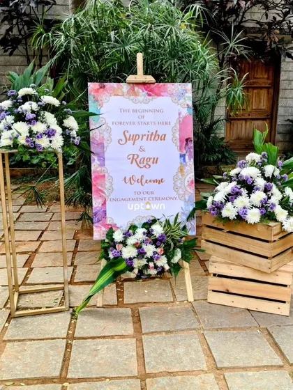 A welcome sign for an engagement ceremony, surrounded by fresh flower bouquets.