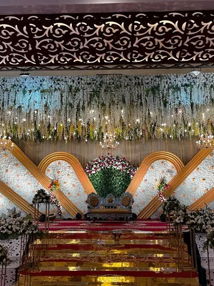To show our range, here is an elegant reception stage we designed. We combine lush floral cascades with beautiful lighting to create a modern and sophisticated backdrop for your evening celebration.