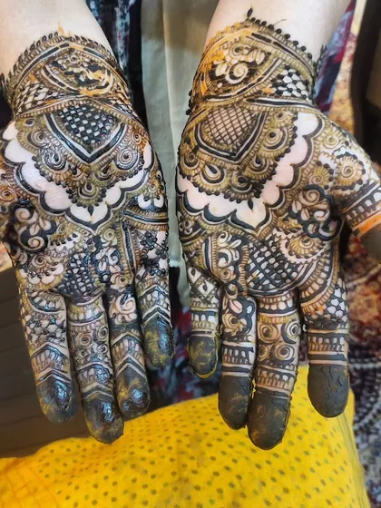 A beautiful design with a central mandala and intricate patterns on the fingers. The dark fingertips add a traditional touch.