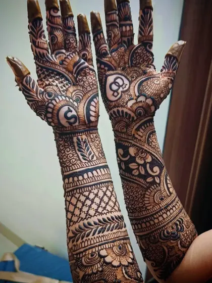 A full-arm bridal design personalized with the initial 'S' on one palm and interlocking rings on the other, symbolizing the couple's union.