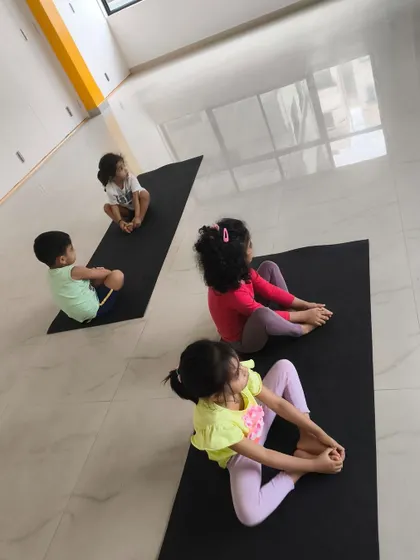 Kids learning the importance of stretching and flexibility on their yoga mats in our bright and clean studio.