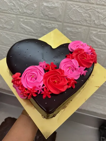 A simple and elegant heart-shaped chocolate cake. It's decorated with beautiful pink and red buttercream roses, making it a classic choice for anniversaries, Valentine's Day, or just to say "I love you."