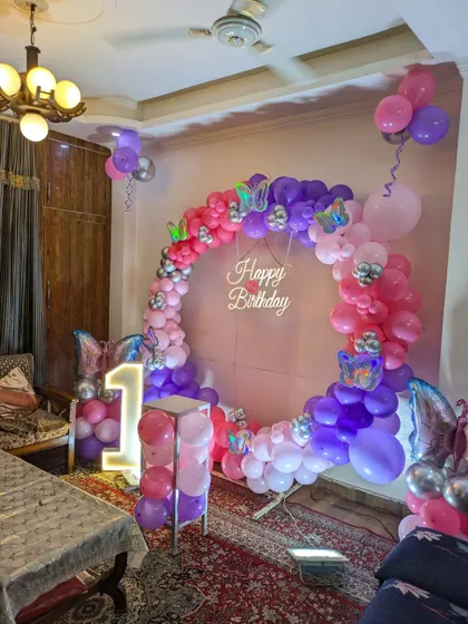 A full view of the butterfly-themed setup in a home, showing the ring backdrop, marquee number, and surrounding balloons.