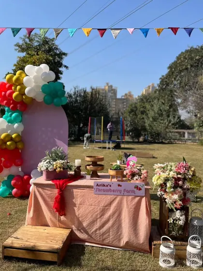 A vibrant strawberry farm themed party setup, with a checkered tablecloth, fresh flowers, and colorful balloons.