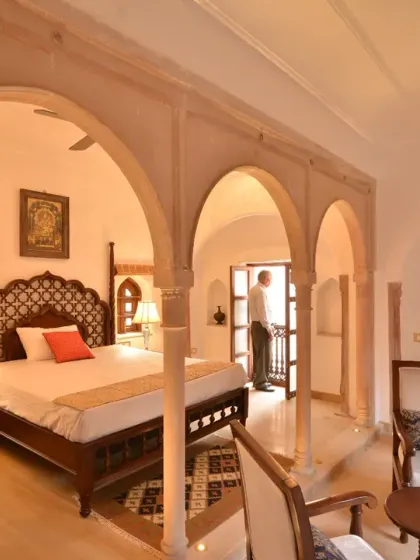 A Diwan-e-Khas room, where traditional decor and antique furniture create a unique atmosphere. The arched openings and windows connect the interior space to the historic bylanes of Chandni Chowk.