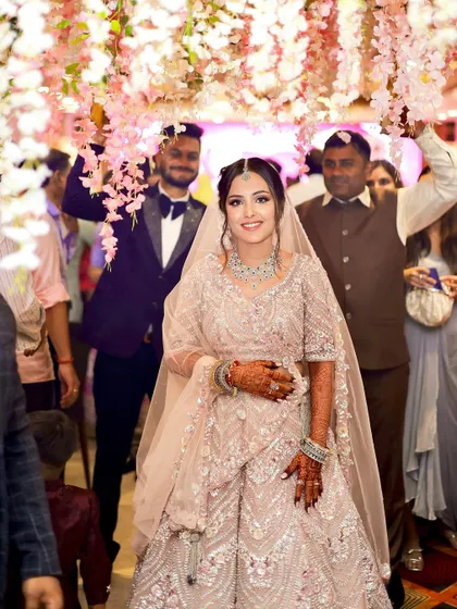 A beautiful bride making her entrance under a floral canopy. Her pastel look is fresh, modern, and absolutely radiant.