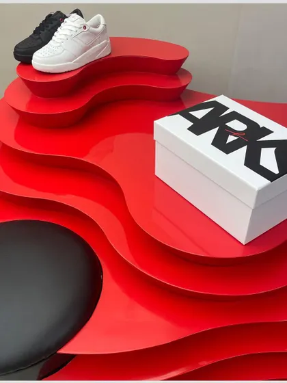A close-up of the custom red display unit, showcasing its glossy finish and undulating form. This piece was designed to be a playful and memorable element within the store's otherwise serene interior.