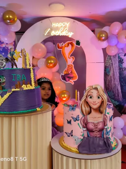 A detailed look at a Tangled themed birthday party, featuring two custom cakes with Rapunzel designs set against a backdrop of the movie's iconic scenes.