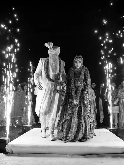 A timeless black and white shot of the couple's Varmala, with cold pyros adding a touch of sparkle and drama to the classic moment.