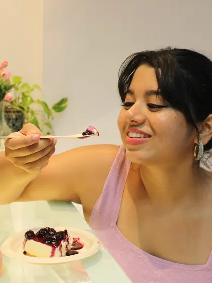 A customer savoring a bite of our best-selling eggless Blueberry Cheesecake. The combination of creamy cake and tangy berry compote is pure bliss.
