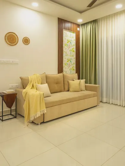 The sofa-cum-bed in 'Bohemian Bliss' is shown here, a practical choice for hosting guests. The olive green curtains and yellow throw add soft splashes of color.