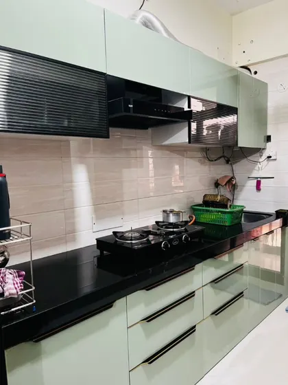 A practical view of the mint-green kitchen, showing the layout with the hob, chimney, and sink. The handleless drawers and cabinets give it a sleek, modern profile.