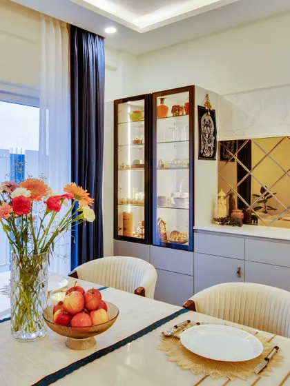 A close-up of the dining area in our Kerala-inspired project, featuring a glass-fronted crockery unit and a bronze-tinted mirror panel.