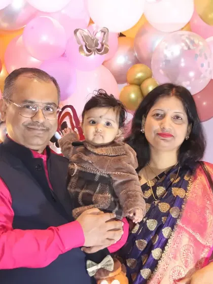 A family of three posing for a classic portrait in front of a pink and gold butterfly-themed balloon wall.