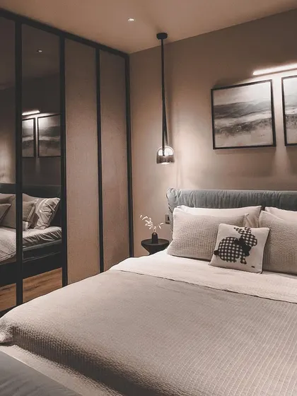 A bedroom concept featuring a black mirrored wardrobe to visually expand the space. The moody color palette and pendant light create a sophisticated and intimate atmosphere.