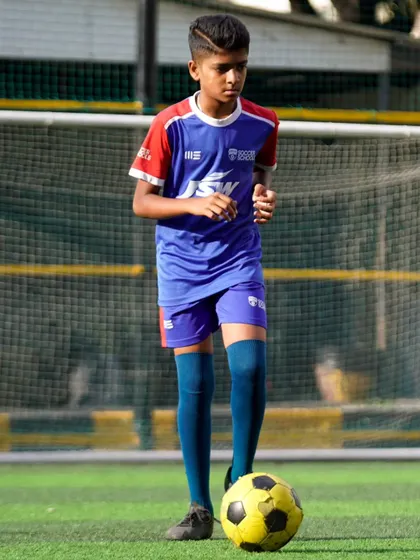 A young player focuses on controlling the ball. Our sessions are designed to maximize touches and accelerate skill development.