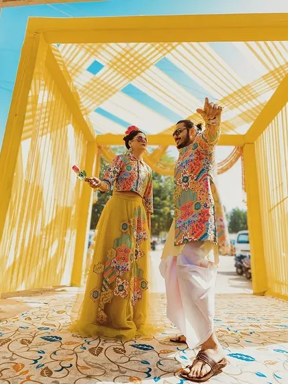 A vibrant and playful moment from a Haldi or Mehendi function. The colorful decor and the couple's fun interaction showcase the joyful side of wedding celebrations.