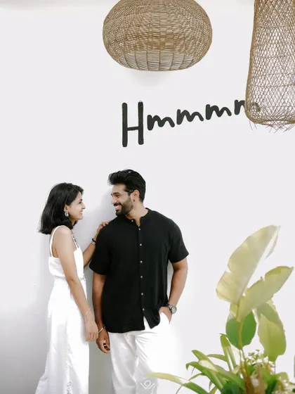 A minimalist and modern pre-wedding shot, capturing a fun, interactive moment against a clean white wall.
