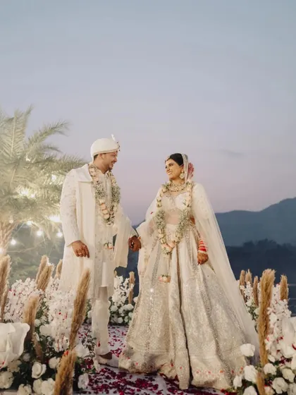 A stunning portrait of the couple on their wedding aisle, surrounded by flowers, with the mountains in the background.