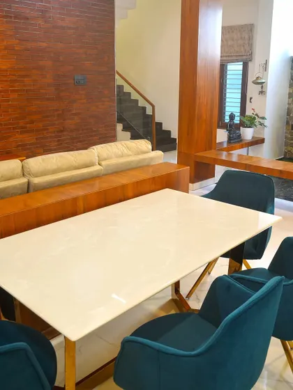 This dining and living area in the Haritha and Harinath residence features a modern tropical theme. We used a brick accent wall and teak wood elements to bring warmth and texture to the open-plan space.