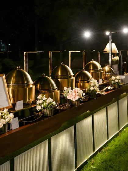 An elegant outdoor buffet setup for an evening corporate gala. Our illuminated counters and polished copper chafing dishes create a sophisticated ambiance while keeping main courses like our signature Hyderabadi Biryani at the perfect temperature.