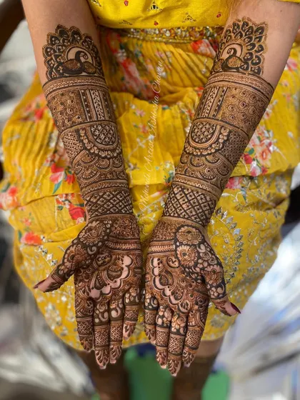 A full bridal mehendi with peacock motifs. The design is intricate and covers the hands and arms in a classic and elegant style.