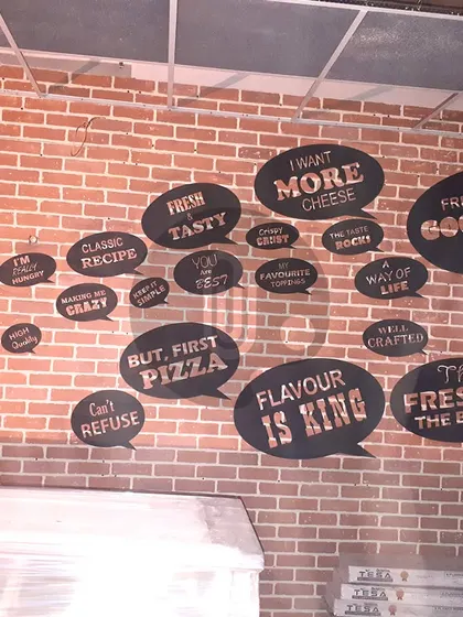 We created this collage of typography bubbles on a brick wall for a pizza place in Dwarka. Each bubble contains a fun, cheese-related phrase, making for an engaging and interactive wall design.