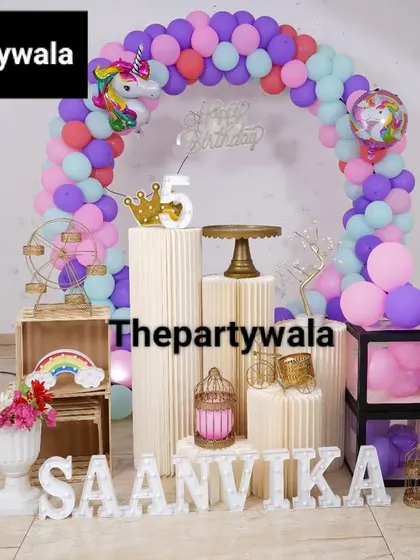 A magical unicorn theme with a pastel rainbow balloon arch. The setup includes unicorn balloons and other whimsical props.