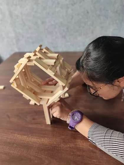 A participant leans in for a closer look, analyzing the structure's balance. This intense focus is common in our workshops, as individuals become deeply invested in solving the physical puzzle in front of them.