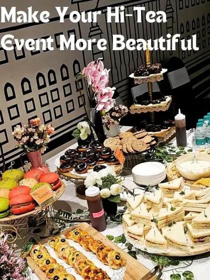 Let me make your hi-tea event more beautiful with an exquisite spread like this. This table features colorful macarons, mini sandwiches, chocolate donuts, and savory bites, creating an unforgettable experience.