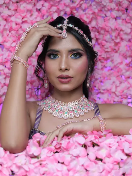 A creative shot with the model surrounded by pink petals. This highlights the romantic and dreamy quality of the makeup and styling.