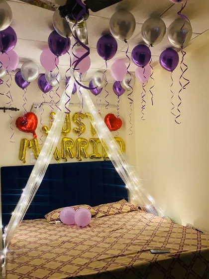 The combination of a lit canopy and ceiling balloons creates a magical and intimate atmosphere for a first night celebration.
